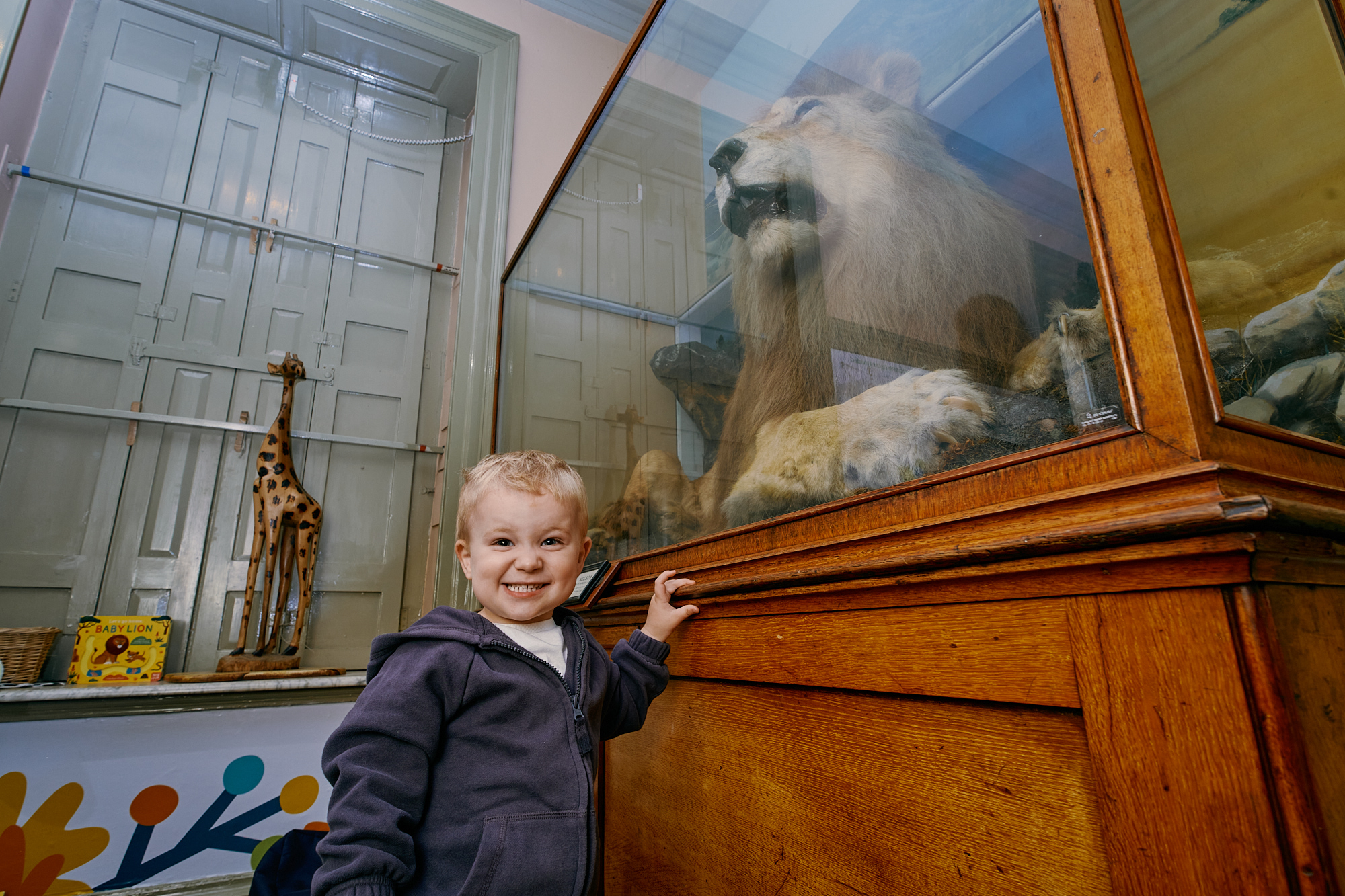 Young boy with blonde hair stood in front of the nelson the lion collection