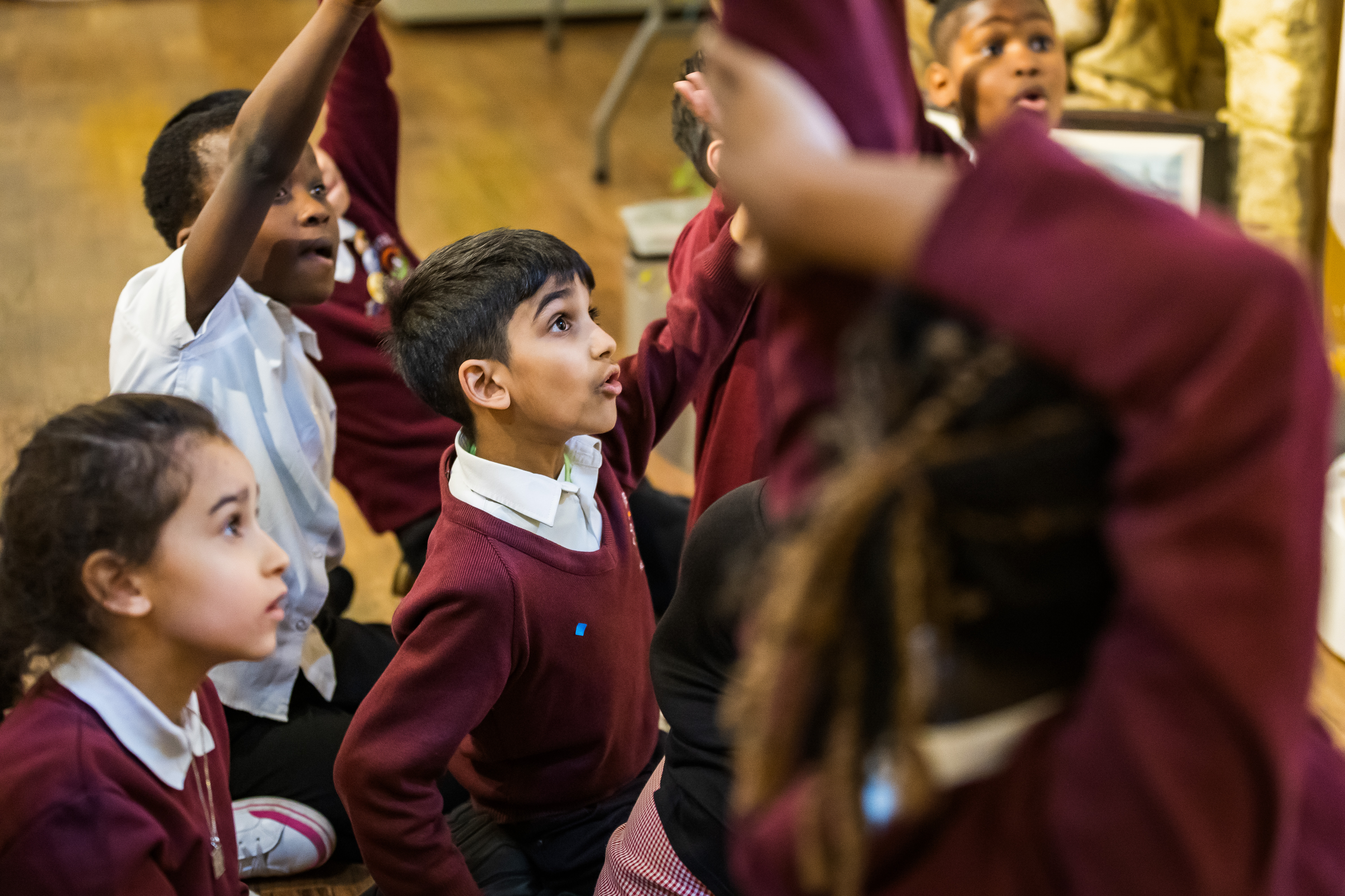 School kids with their hands up to ask questions