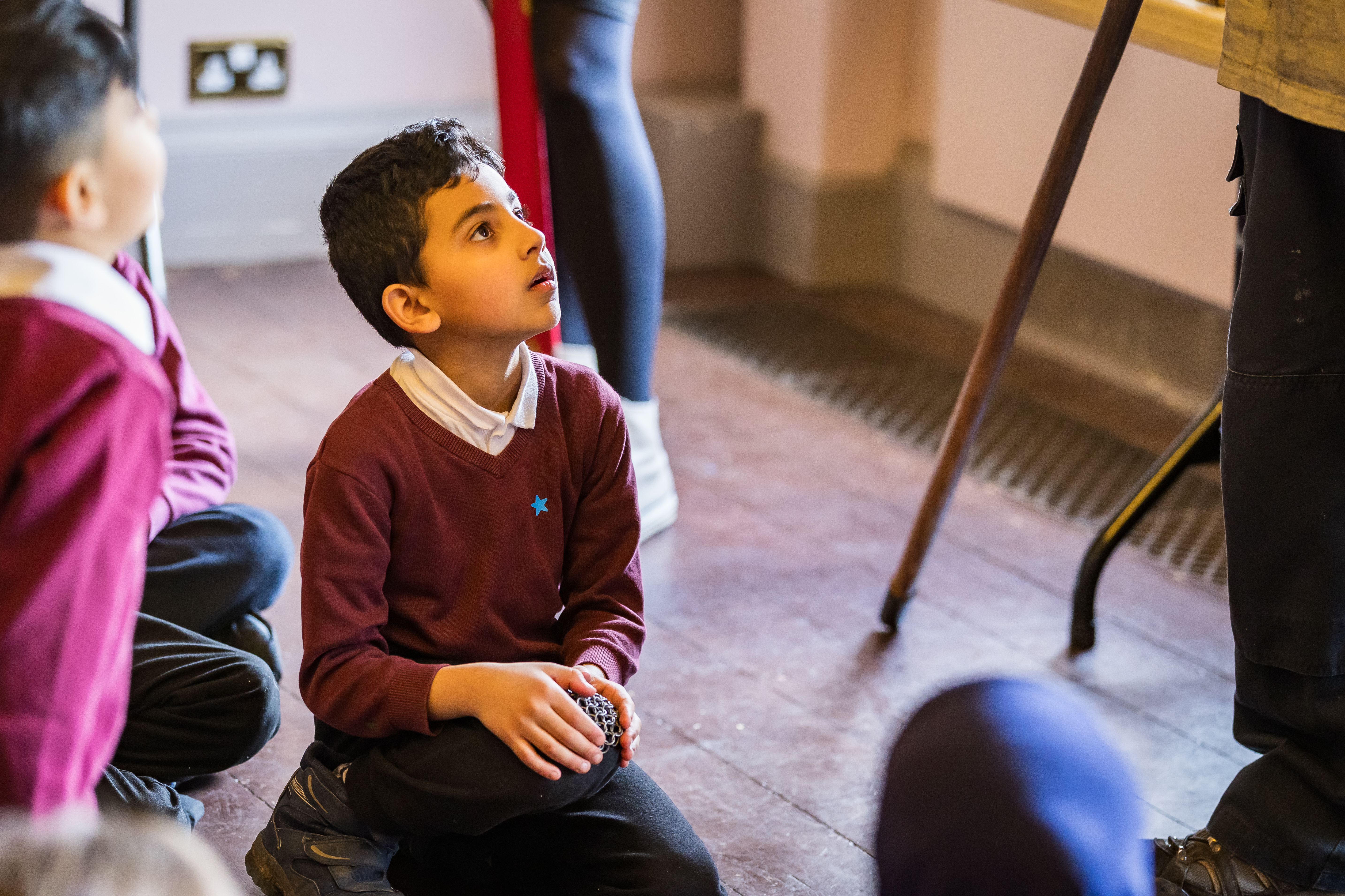 School kids sat on the floor listening to a teacher